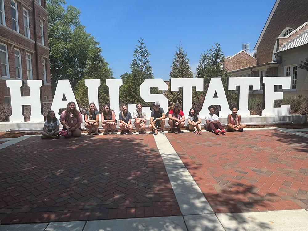Design Discovery campers pose for a picture in front of the &quot;Hail State&quot; sign.