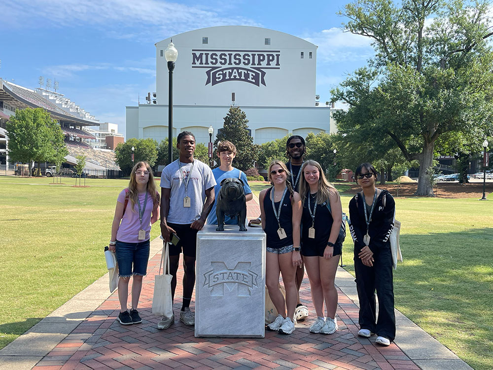 Design Discovery campers pose for a picture by the bulldog statue, in front of the Davis Wade stadium.