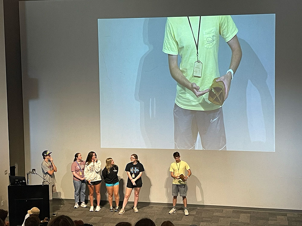 Group of Design Discovery campers presenting their project to an auditorium full of Design Discovery campers.