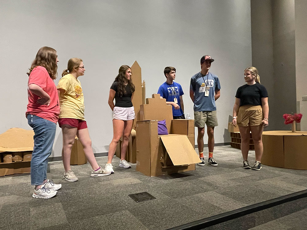 Design Discovery campers present their cardboard chair project in the auditorium.