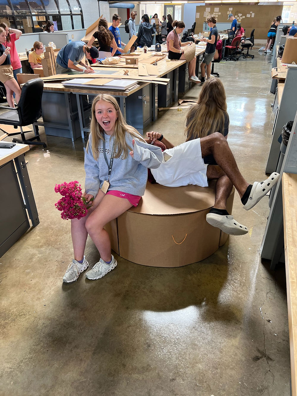 Design Discovery campers sit and lay down on their cardboard chair project in Barn.