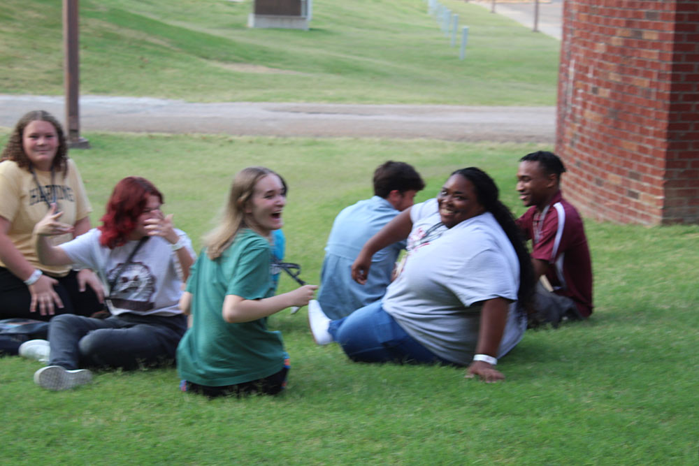 Design Discovery campers sit outside after finishing their human knot game.
