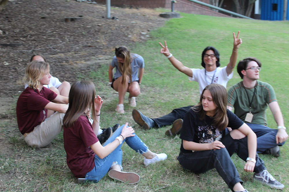 Design Discovery campers sit outside after finishing their human knot game.