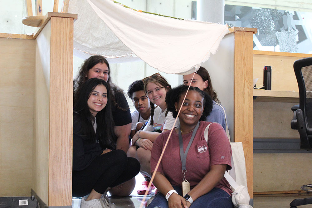 Group of Design Discovery campers and student counselor posing under their instant environment project.