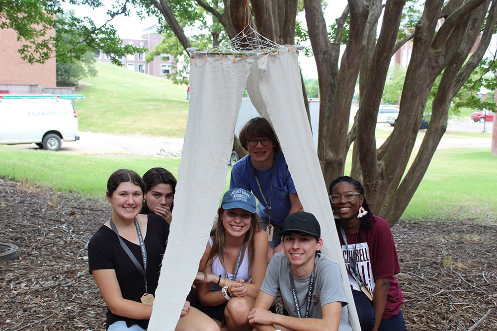 Group of Design Discovery campers posing under and by their instant environment project.