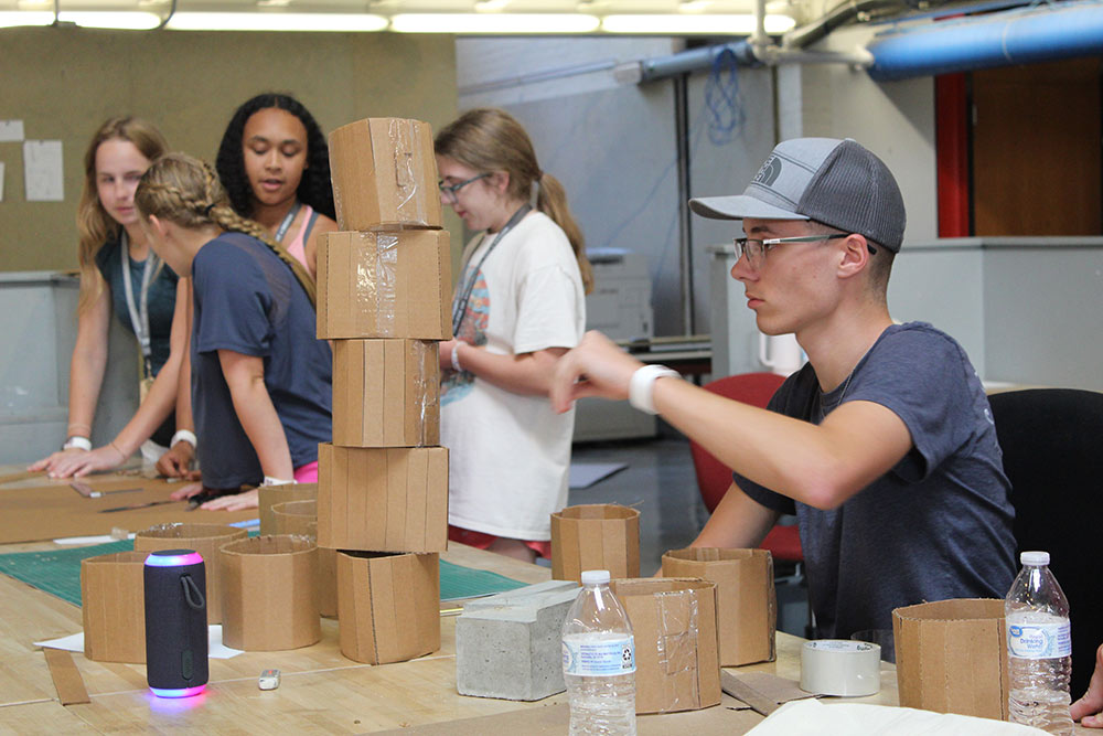 Design Discovery campers work on their cardboard chair project at a desk in Barn.