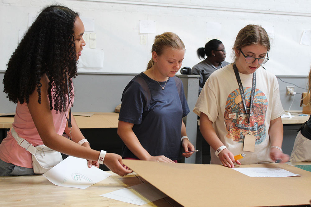 Design Discovery campers work on their cardboard chair project at a desk in Barn.