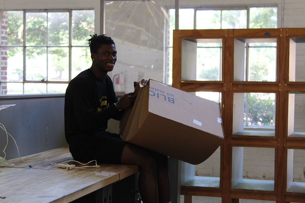 Design Discovery camper works on his cardboard chair project at a desk in Barn.