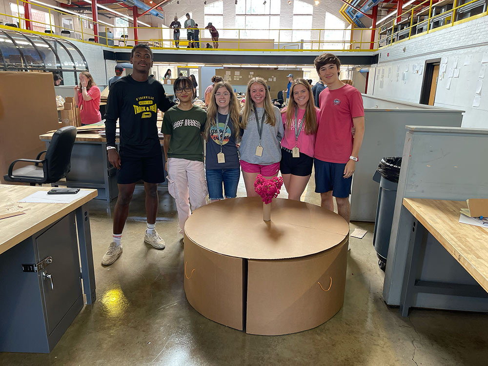 Group of campers pose behind their cardboard chair project.