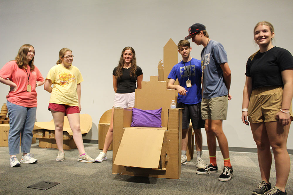 Group of campers stand around their cardboard chair project.