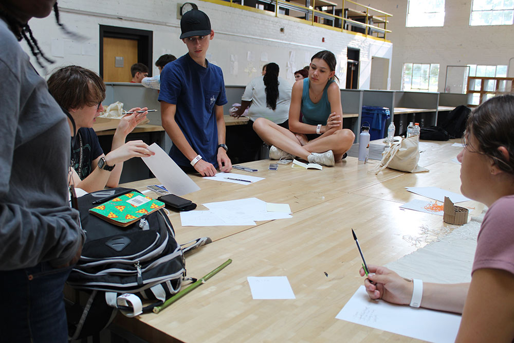 Design Discovery campers discussing ideas at a desk in Barn.