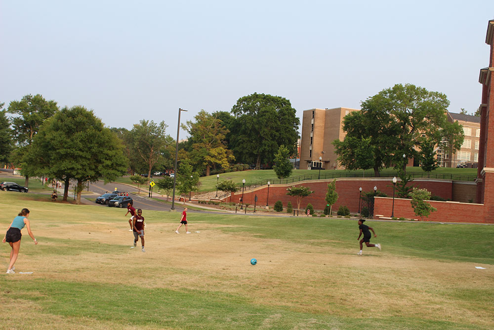 Design Discovery campers playing soccer in a grassy field outside.