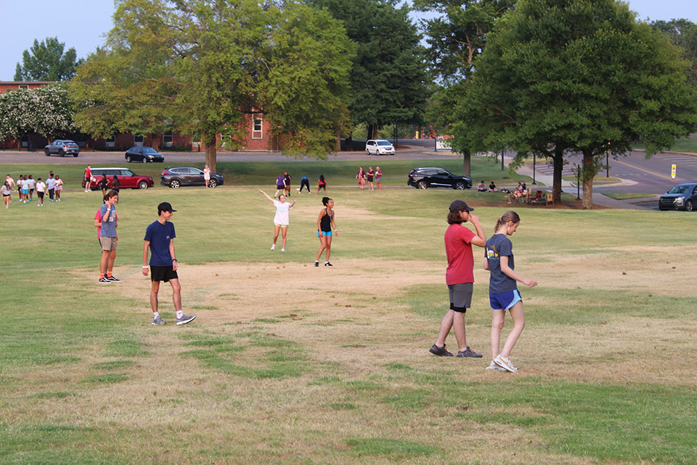 Design Discovery campers playing soccer in a grassy field outside.