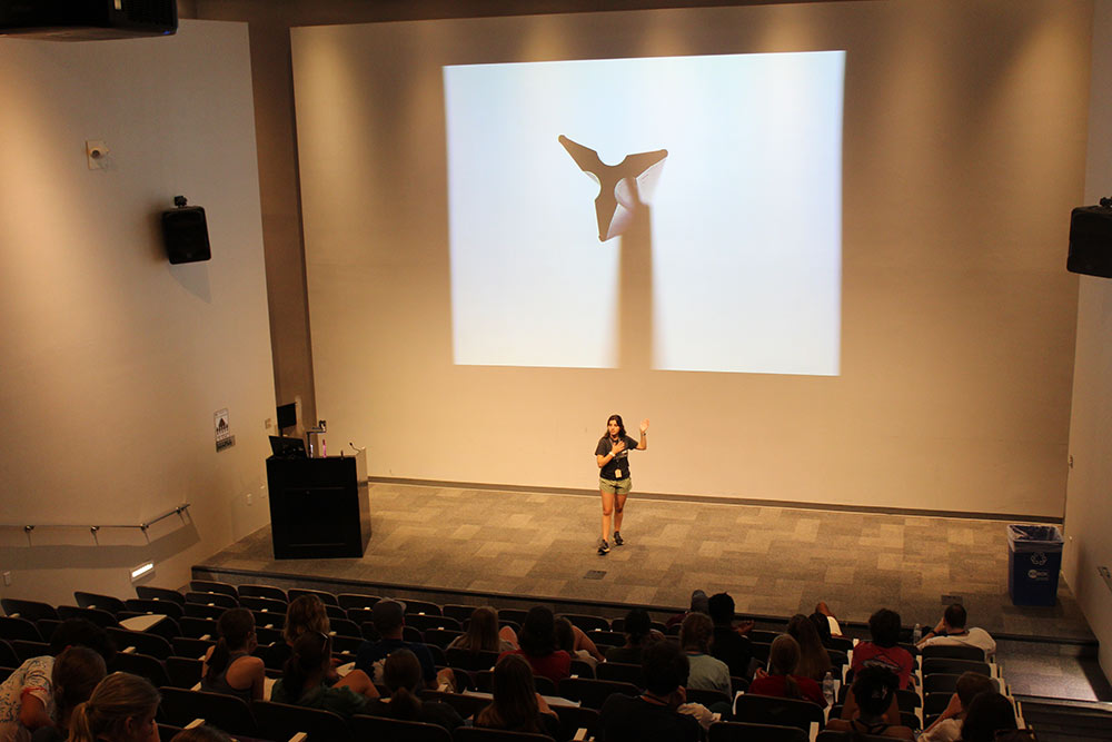 A presenter speaks to the Design Discovery campers in the auditorium.