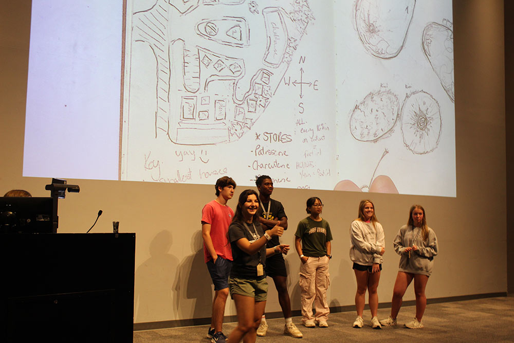 A group of Design Discovery campers presenting their sketches on the projector in the auditorium.