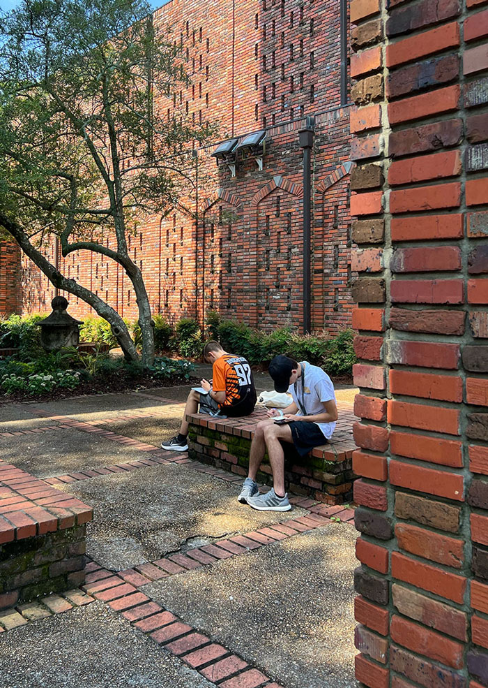 Group of Design Discovery campers sitting in the Courtyard of the Chapel of Memories, sketching in their notebooks.