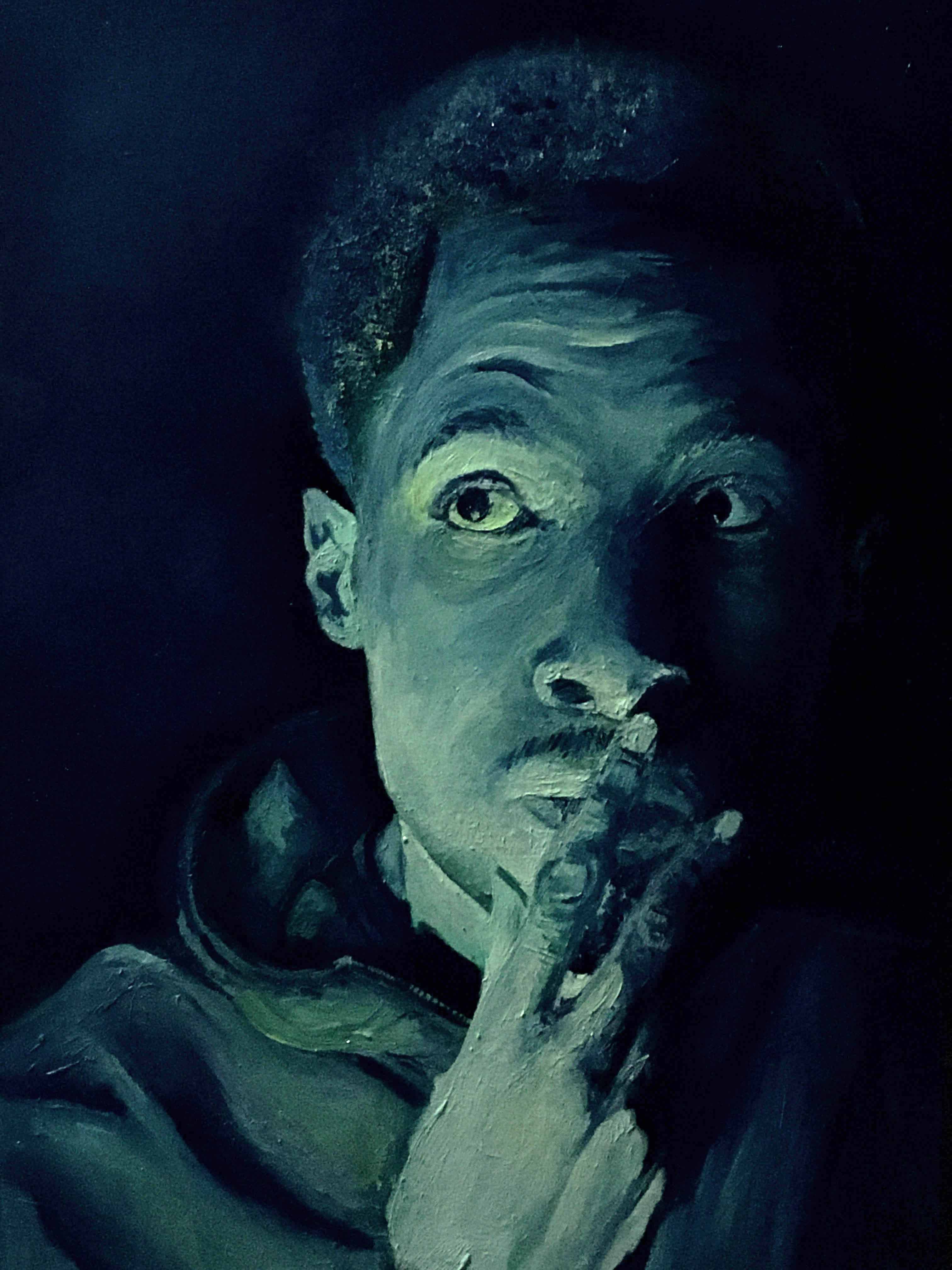A man has his hands over his mouth in thought. He is in a dark room, but glowing light lights his face.