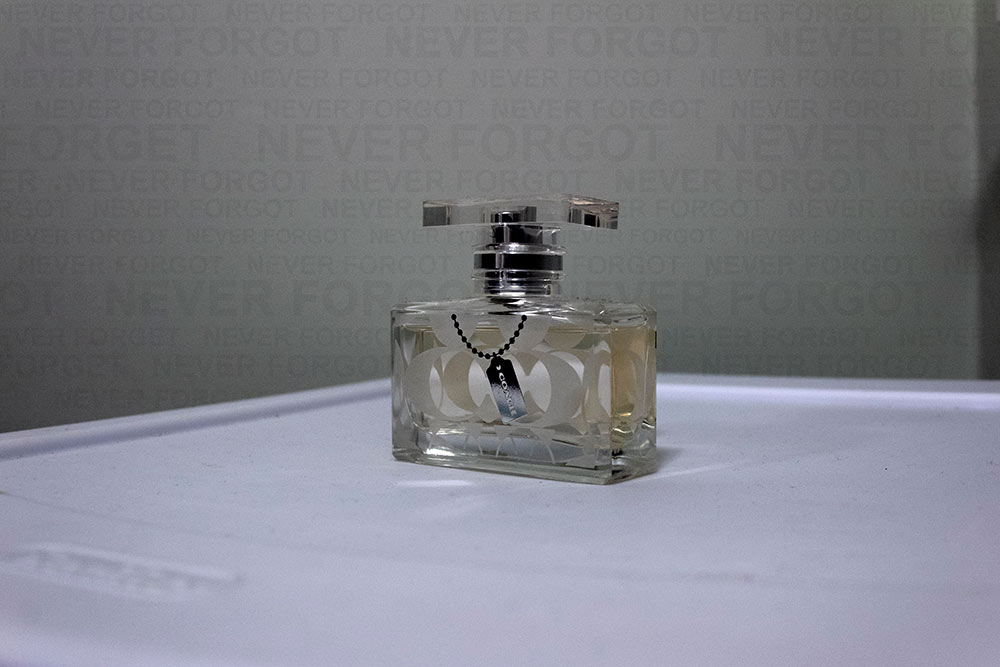 Coach perfume on white table - "Never forgot" repeated across background