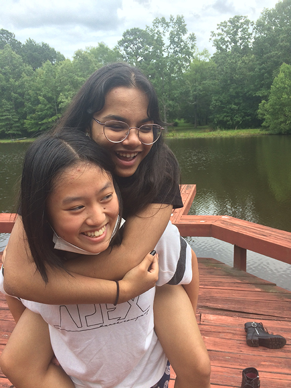 Image of two laughing girls, one giving the other a piggy-back ride.
