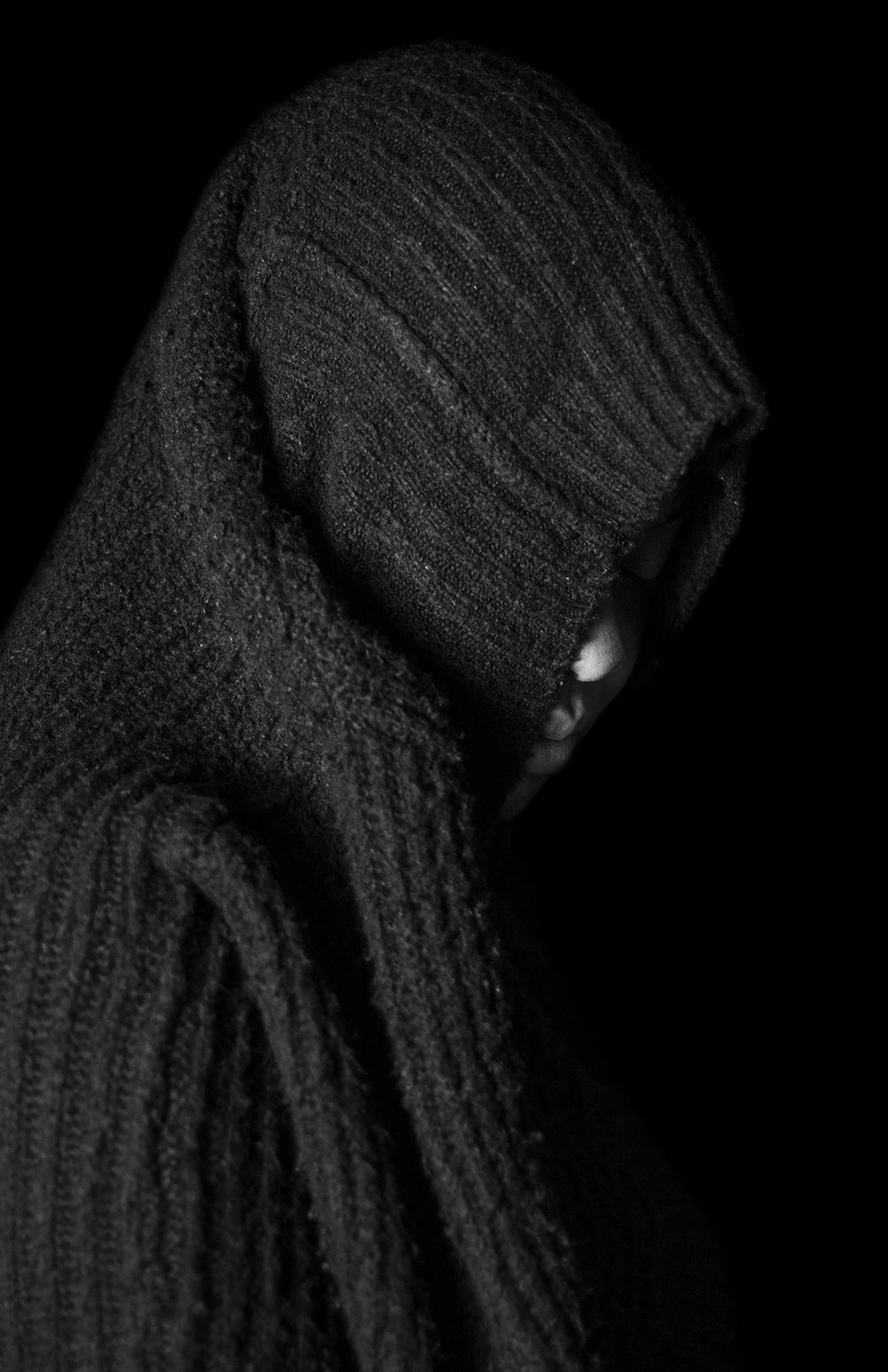 black and white shot of person covering head with sweater hood