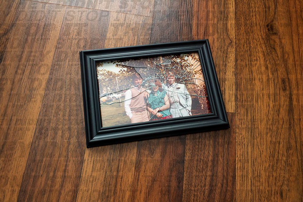 shattered picture frame with 3 people inside - on wood floor is written: "they didn't stop it"