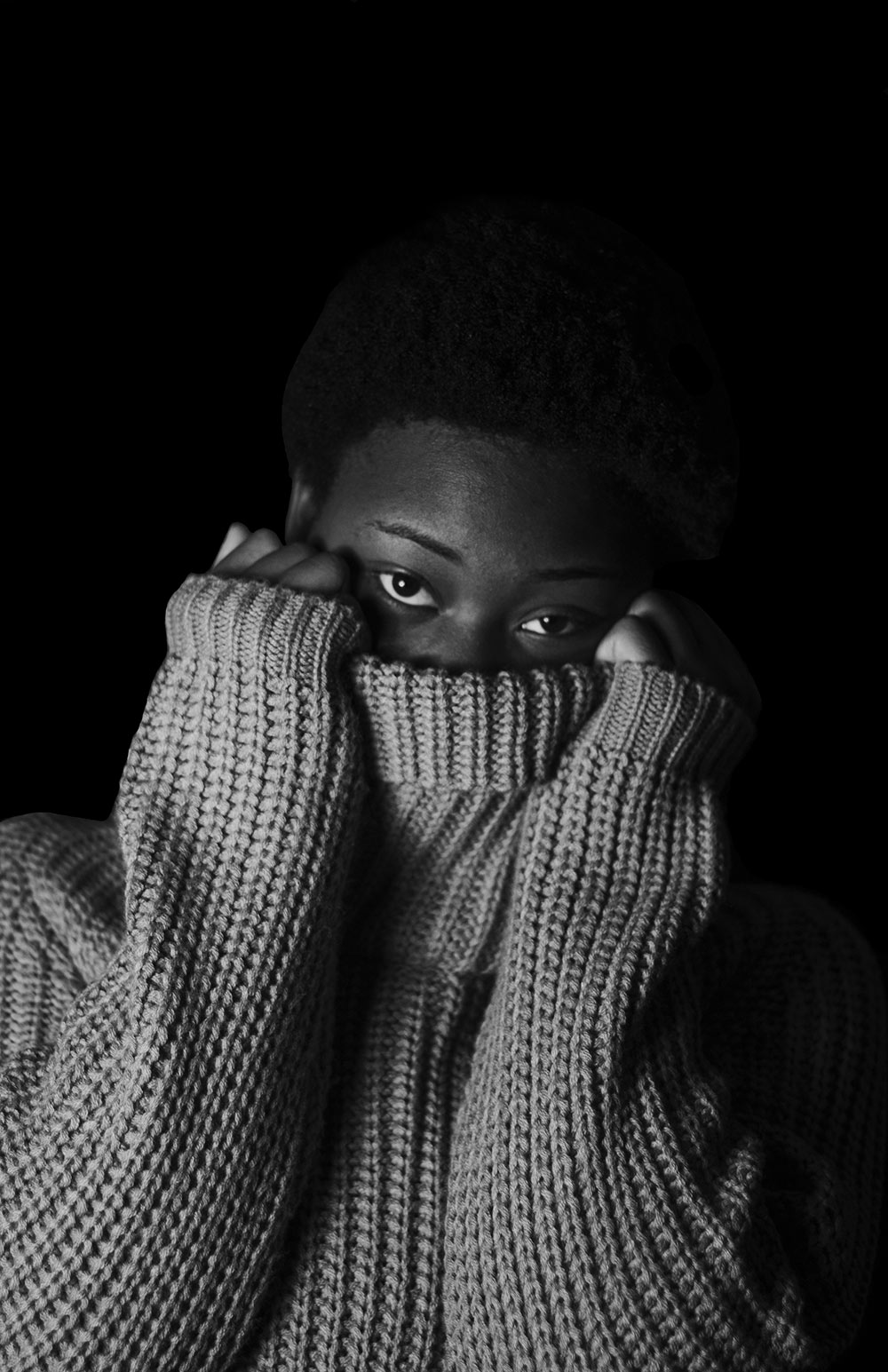 black and white shot of person covering bottom of face with sweater