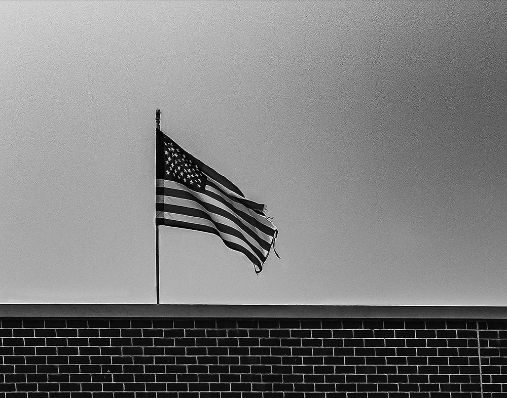 black and white image of top of brick wall with American flag on top