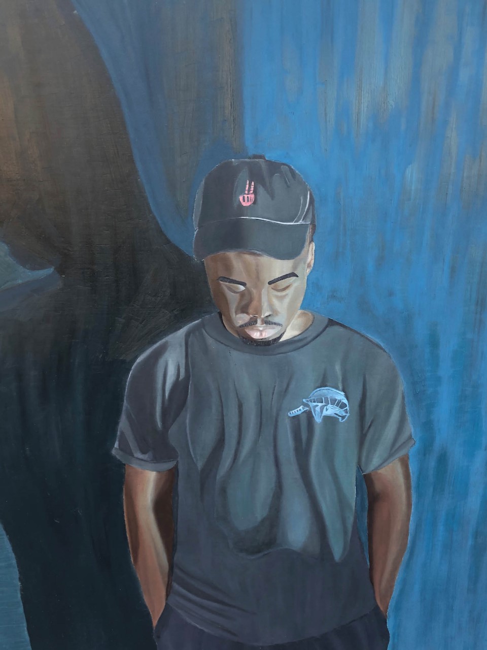 African American male friend emphasizing an emotion of calmness. Wearing a warm blue colored shirt, with dark black colored pants. Incorporating multiple areas of warm tone blues onto the skin of the face, neck, hands, and arms. Also, having a shade silhouette behind the male figure. Warm and cool tones of blues on the background to compliment both the figure and the emotion of calmness. Detailed and textural areas within the shirt, shorts, arms, face, and background. 
