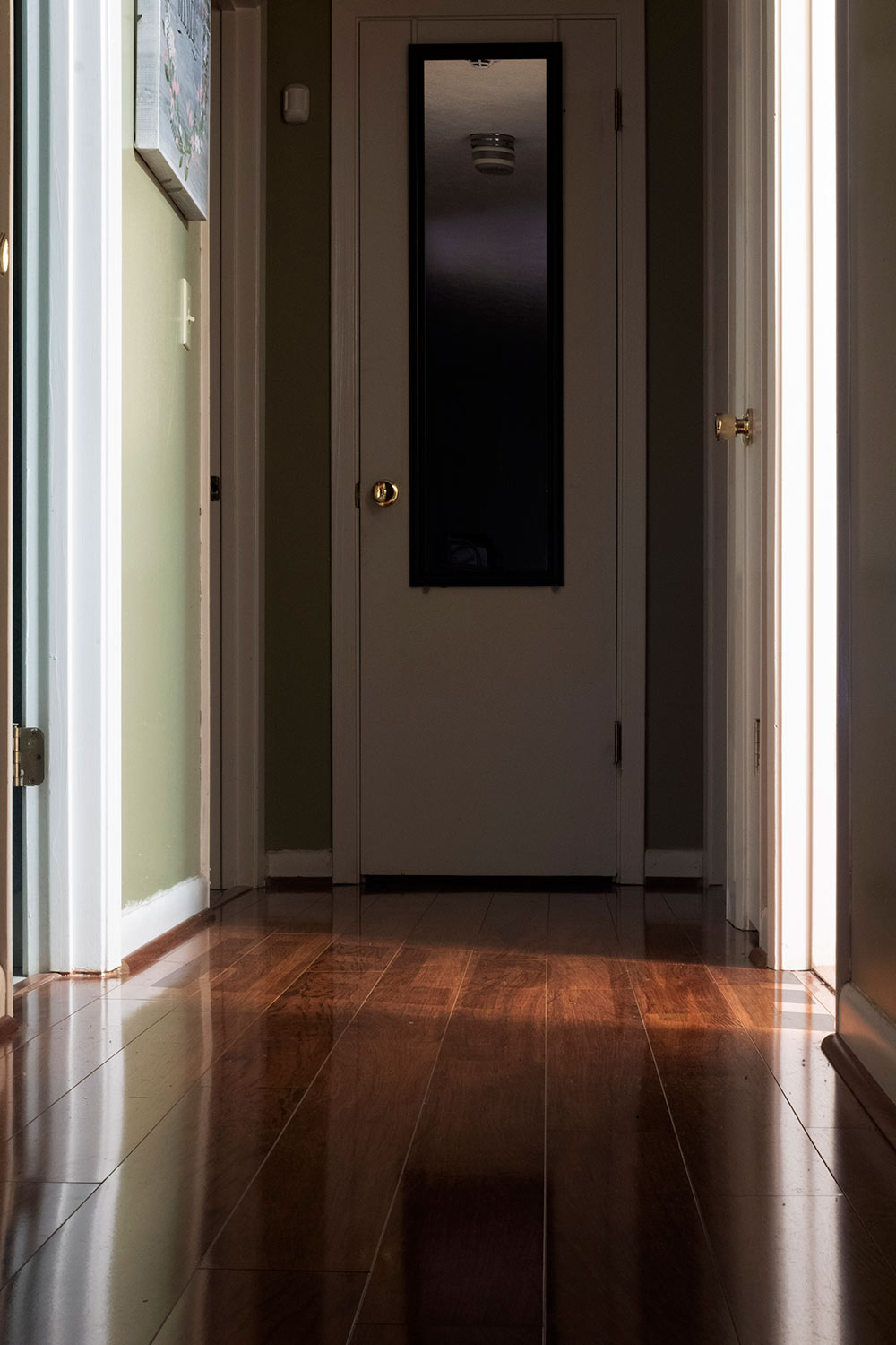 view of a hallway with door at back. help me written across floor
