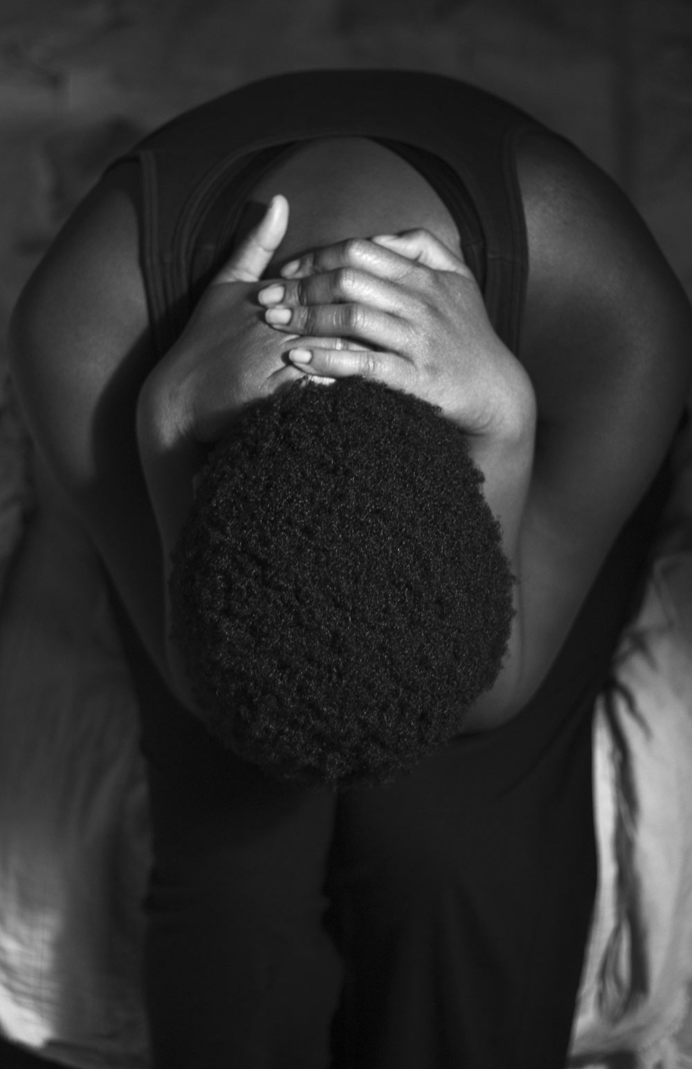 black and white shot of person leaning over and hands on back of neck