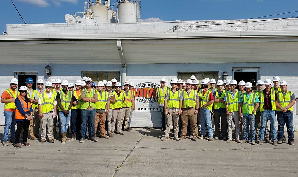 Mississippi State University School of Architecture building construction science majors in first-year studio pose in safety gear (hard hats, vests) in front of MMC building