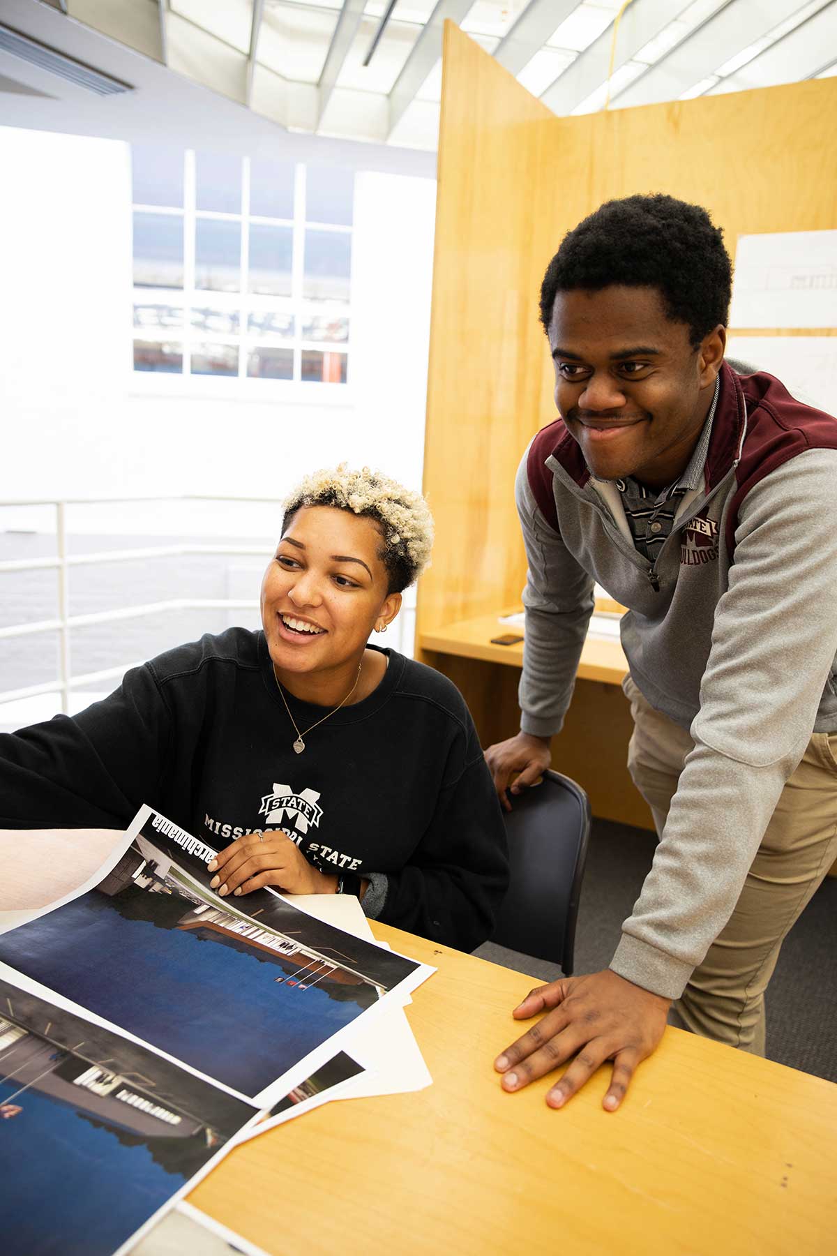 Senior architecture major Mariah Green, left, sitting, points out something in the exhibit to classmate Caleb Shaw