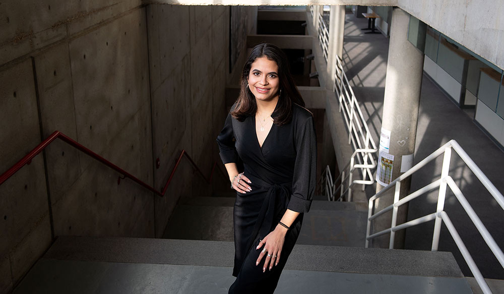 Elisa Castaneda poses (standing) on the stairs in Giles Hall