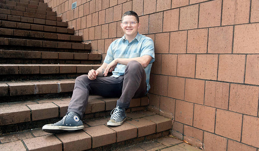 Luke Murray sits on steps outside of Giles Hall