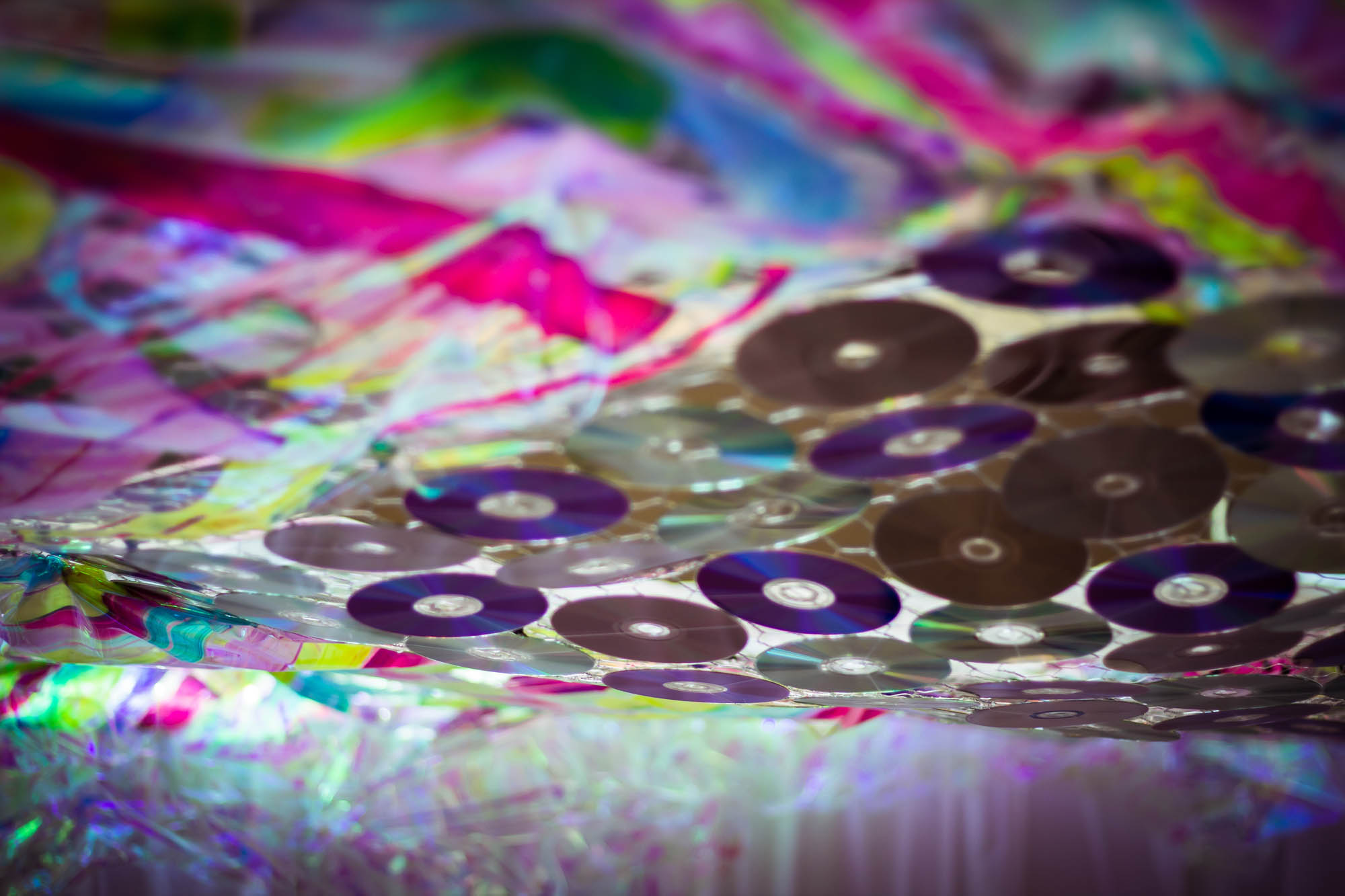 The artist layered cellophane surrounding a sheet of CD’s in the center. Creating a never ending portal of colorful kaleidoscope rainbows.
