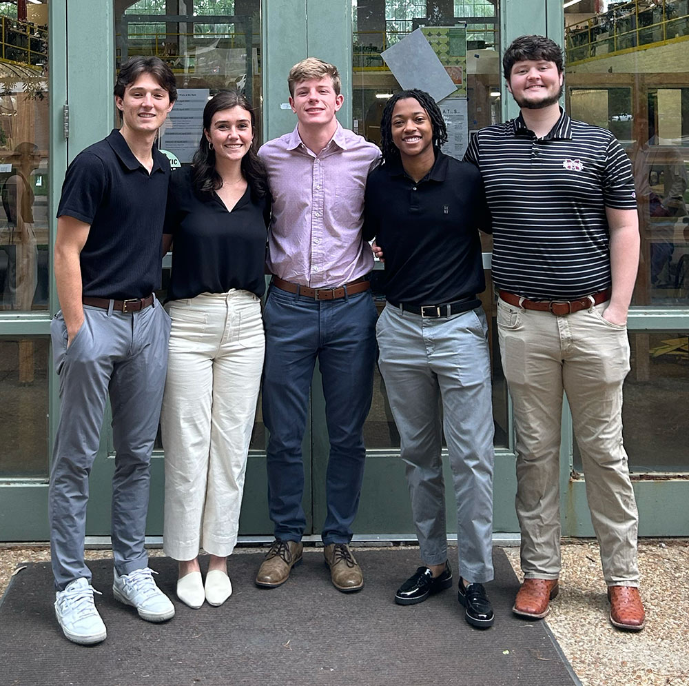 Students gather in front of door for photo: Caleb Clearman (architecture), Abby Mickholtzick (architecture), Luke Douglas (architecture), Nya Hatcher (building construction science), William Carwile (building construction science)
