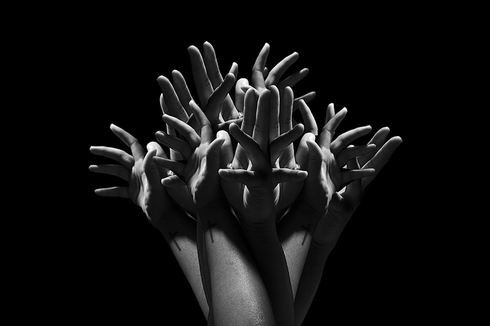black and white image of hands all together with fingers sticking out like a tree