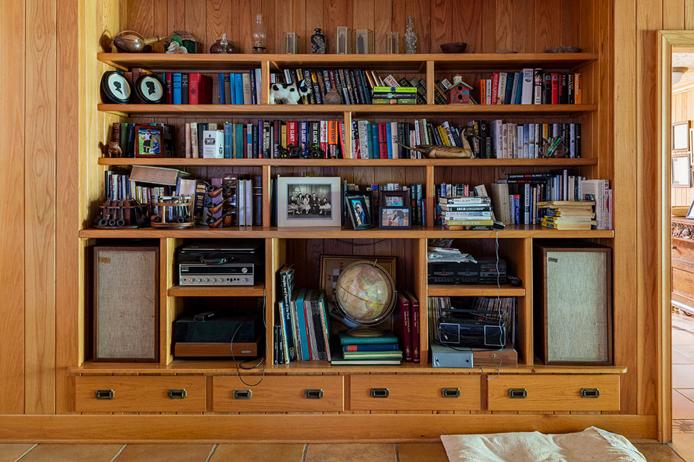 wooden built in shelf full of books, photos, a globe, etc.