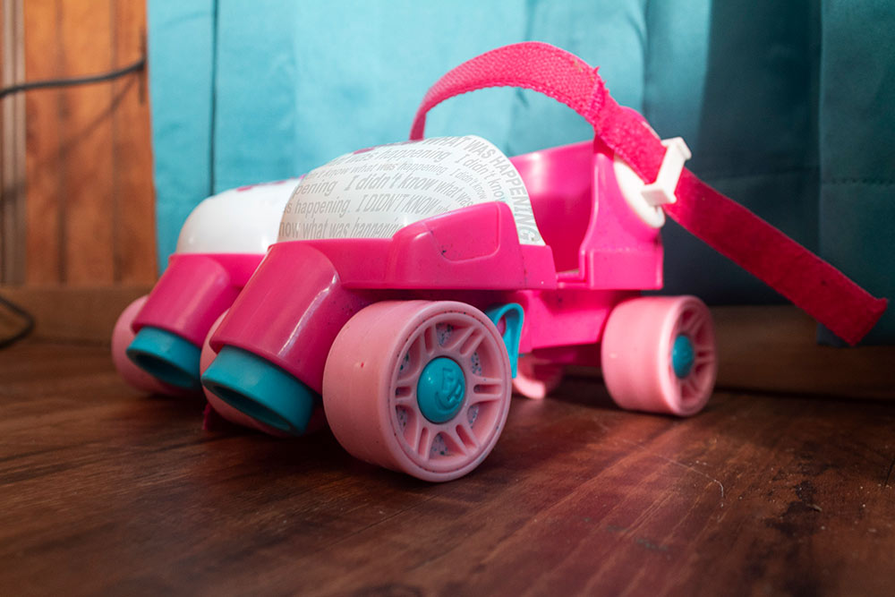 pink and teal plastic roller skates that strap to shoes "I didn't know what was happening" written on front