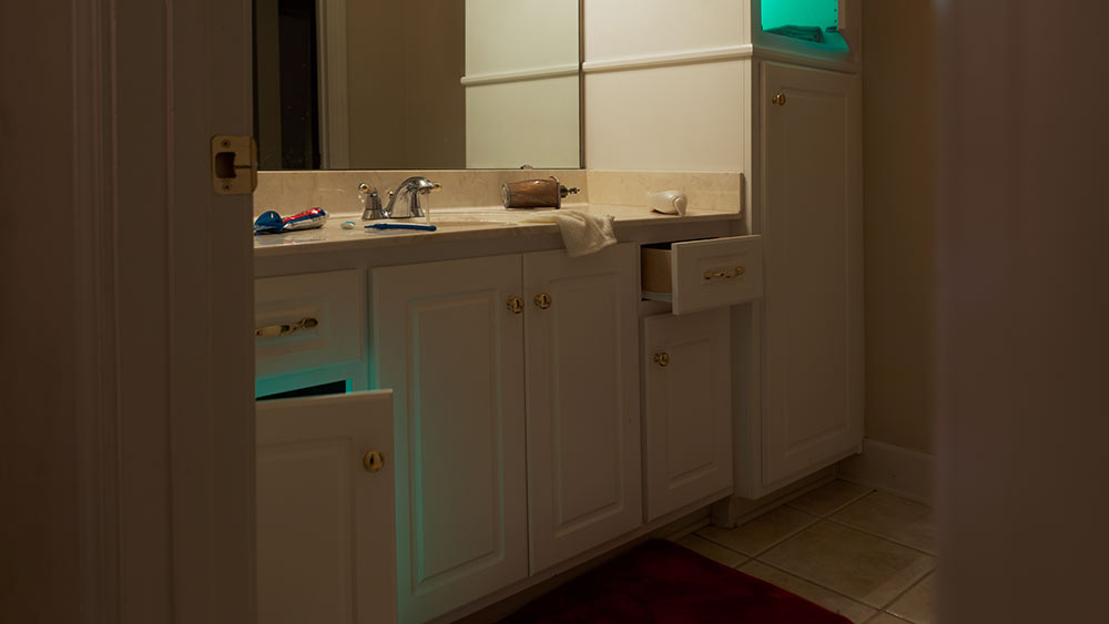 bathroom cabinets; a few are open with green glowing light