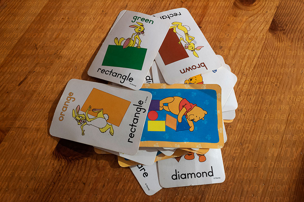 stack of children's playing cards on wood floor "why didn't they believe me" written on floor in repeat