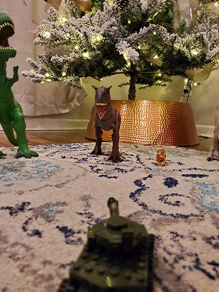 Photograph of a toy dinosaur under a Christmas tree