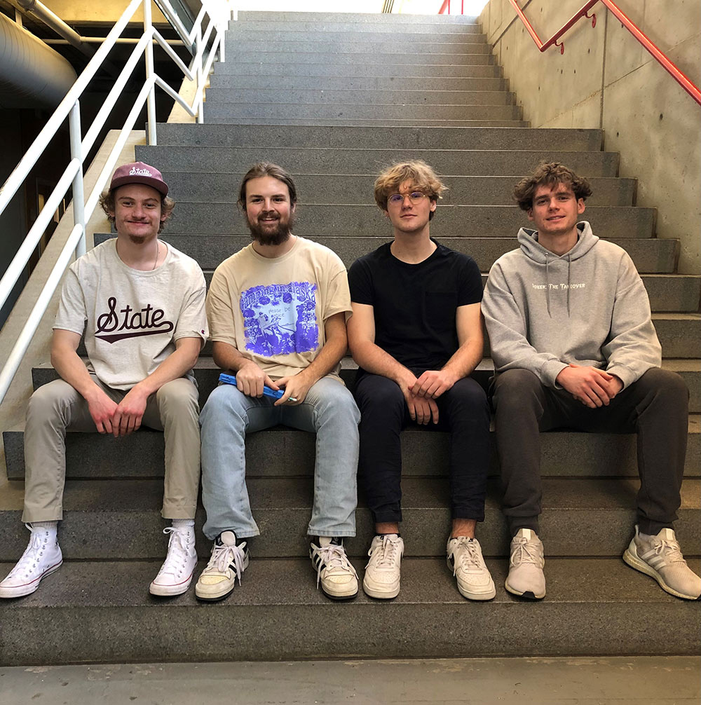 students sit on steps, left to right: Alaster Redmond, John Michael Gray, Peter Fox and Ryan Kubinski 