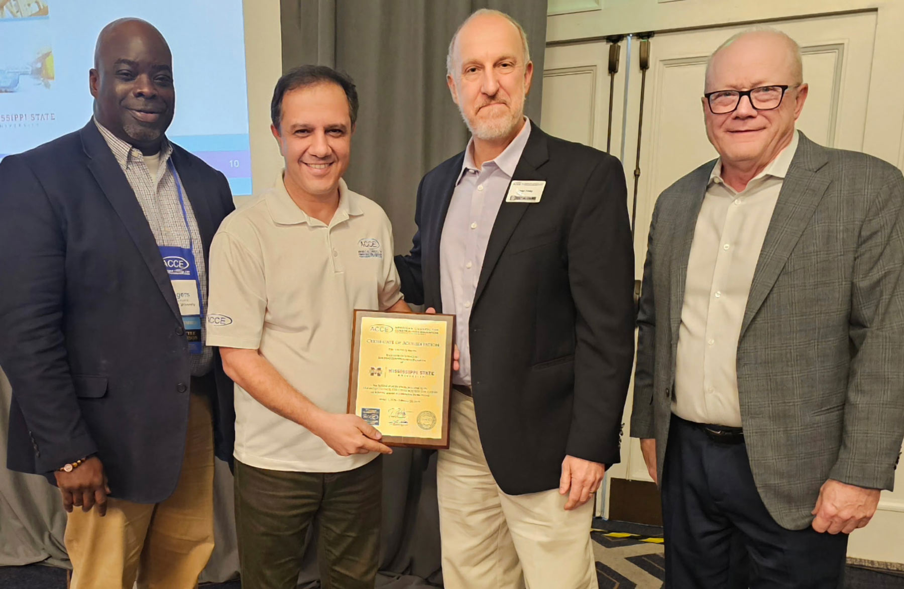 Men pose with plaque. Pictured, left to right: Rogers Hunt III, Chair of ACCE Board of Trustees; MSU Associate Professor Saeed Rokooei, BCS Accreditation Coordinator; Sean Foley, Chair of ACCE Accreditation Committee; Steve Nellis, President & CEO of ACCE