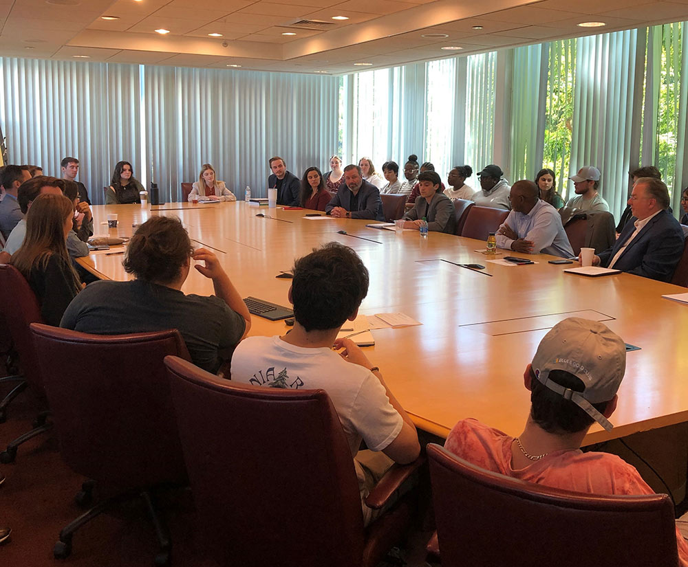 people sit around long table in room with window