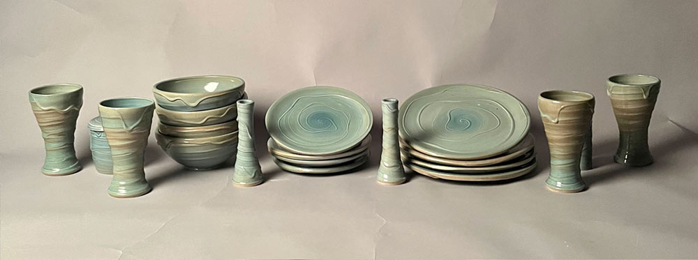 Light blue dinnerware set with four dinner plates, four dessert plates, four bowls, four cups, two candlesticks, one butter bell, salt ‘n’ pepper shakers, and one pitcher.