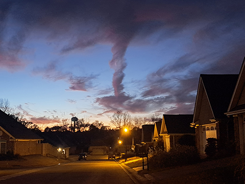 Photograph of the sky at dusk over a neighborhood of houses.