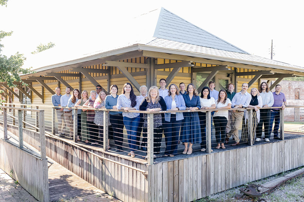 Belinda Stewart Architect employees gathered on a top story porch pose for a group photo