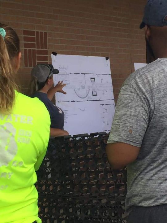 view of people looking at plans as woman points to them