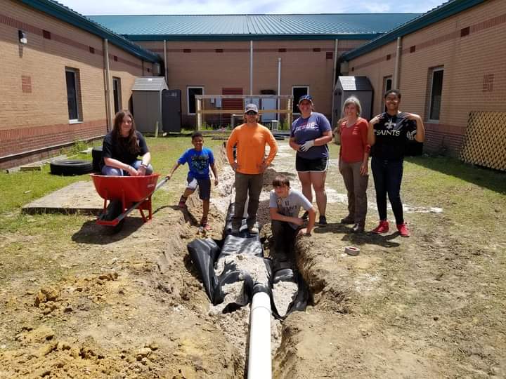 group poses outside of school by garden project